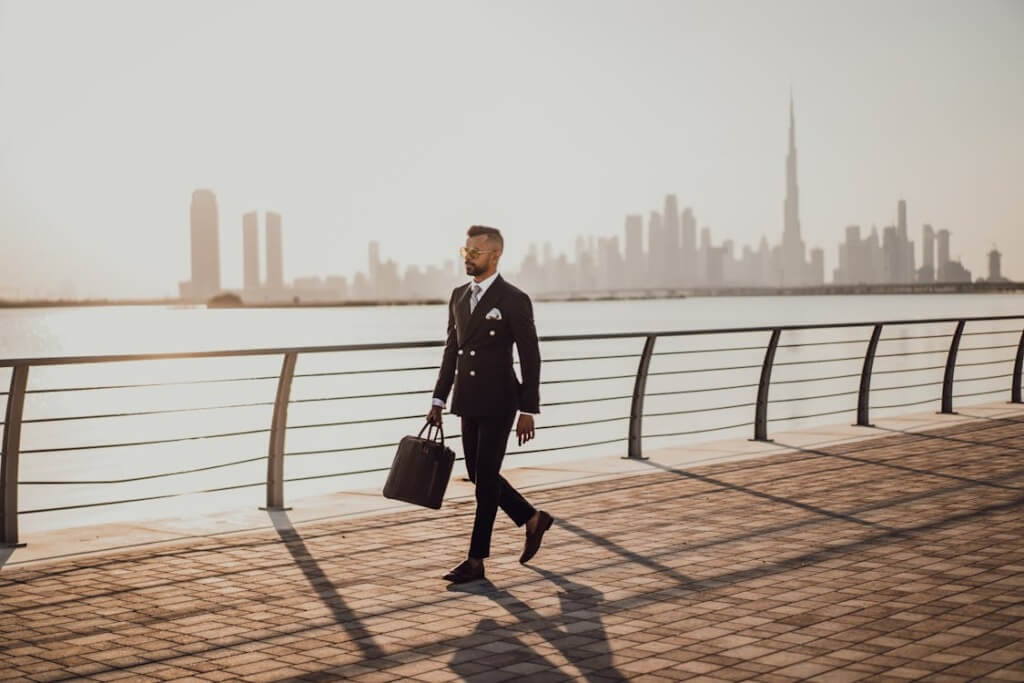 A well-suited man walking on corniche side.
